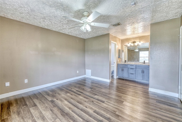 interior space with dark wood-style floors, visible vents, connected bathroom, and baseboards