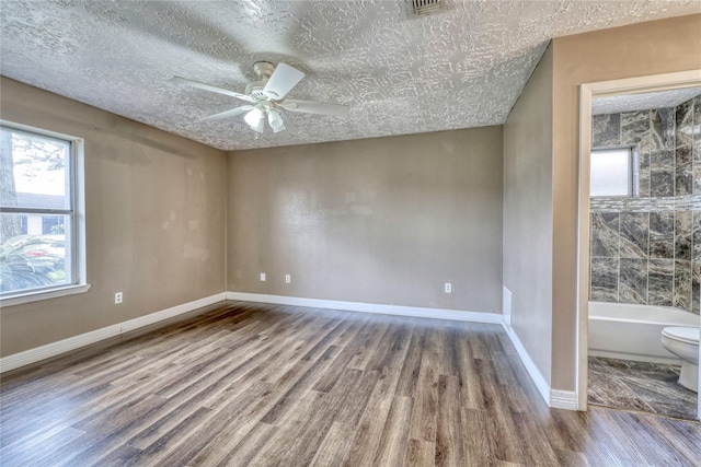 spare room with ceiling fan, a textured ceiling, baseboards, and wood finished floors