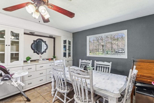 dining room with light tile patterned floors, a ceiling fan, and a textured wall