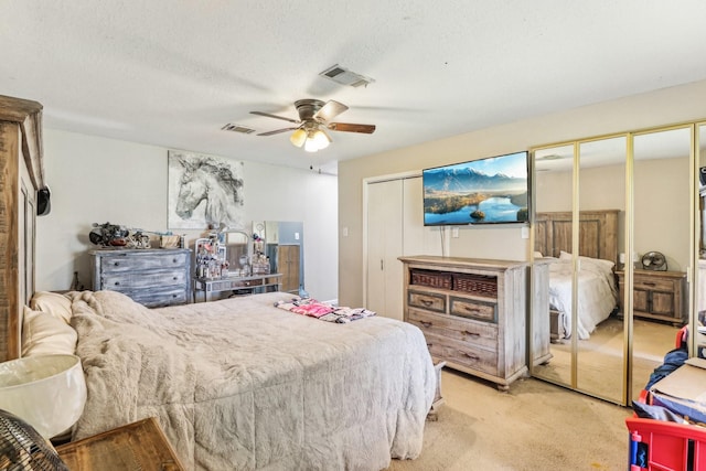 bedroom with visible vents, carpet floors, a textured ceiling, and multiple closets