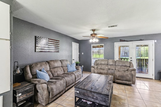 living area featuring visible vents, ceiling fan, french doors, a textured wall, and light tile patterned flooring