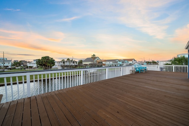 deck at dusk featuring a residential view and a water view