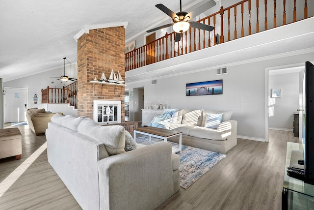 living room featuring visible vents, wood finished floors, crown molding, and stairway