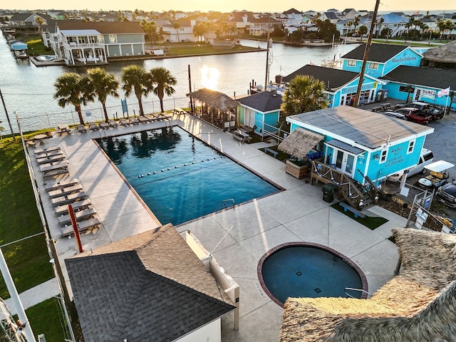 community pool with fence, a residential view, and a water view