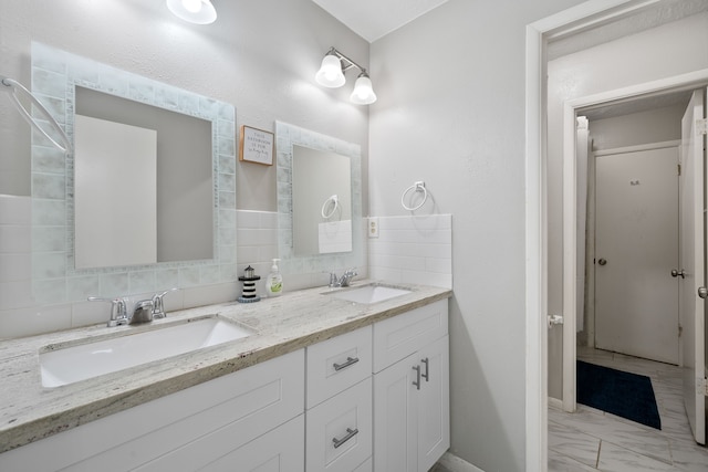 full bathroom featuring decorative backsplash, double vanity, marble finish floor, and a sink