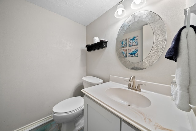 half bathroom with vanity, toilet, baseboards, and a textured ceiling