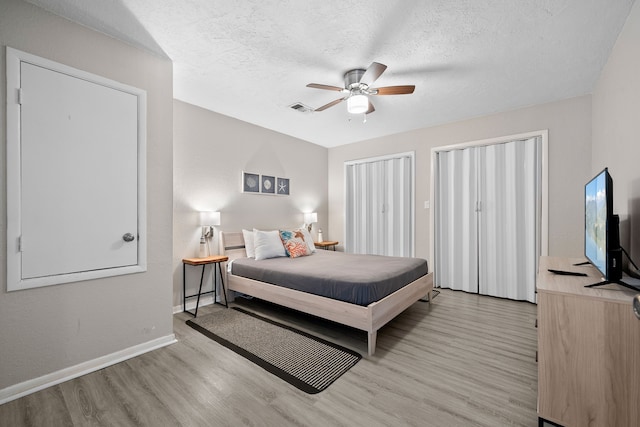 bedroom with light wood-style flooring, baseboards, visible vents, and a textured ceiling