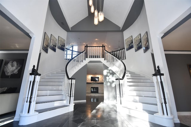 stairs with baseboards, high vaulted ceiling, a fireplace, and tile patterned flooring