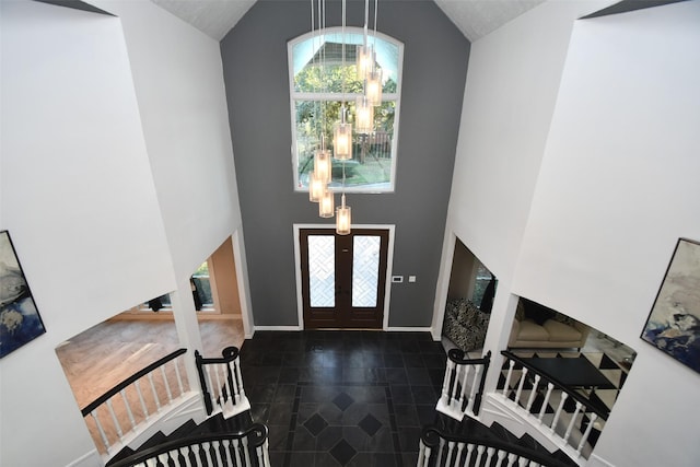 tiled foyer entrance with french doors, high vaulted ceiling, stairs, and baseboards