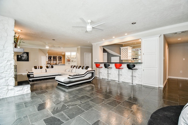 living room featuring a textured ceiling, a bar, crown molding, and ceiling fan