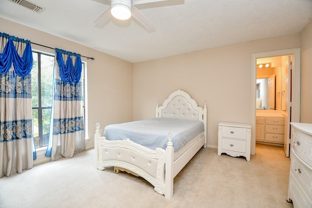 bedroom featuring visible vents, light carpet, ensuite bath, and a ceiling fan