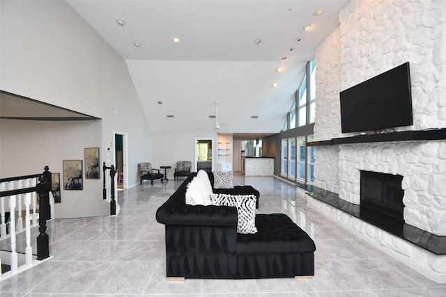 living room with a stone fireplace, recessed lighting, and high vaulted ceiling