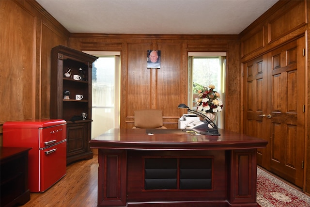 office area with light wood finished floors and wood walls