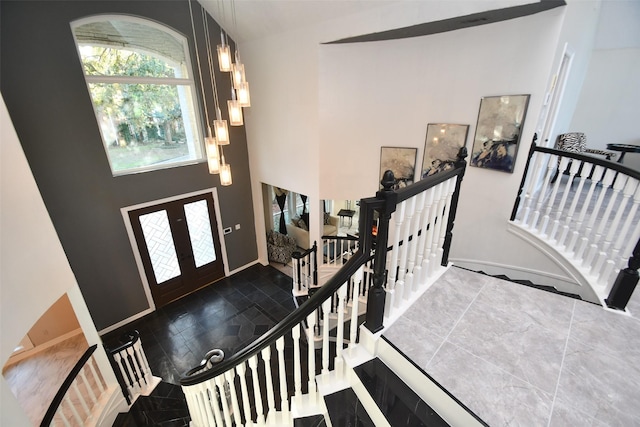 foyer featuring stairway, baseboards, a towering ceiling, and french doors