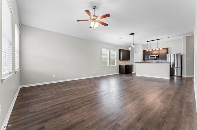 unfurnished living room featuring baseboards, dark wood-type flooring, and ceiling fan