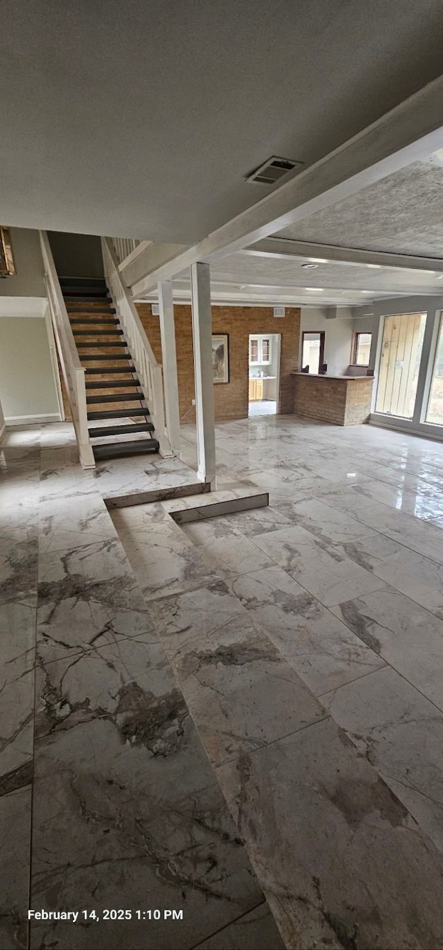 basement featuring visible vents, marble finish floor, and stairs