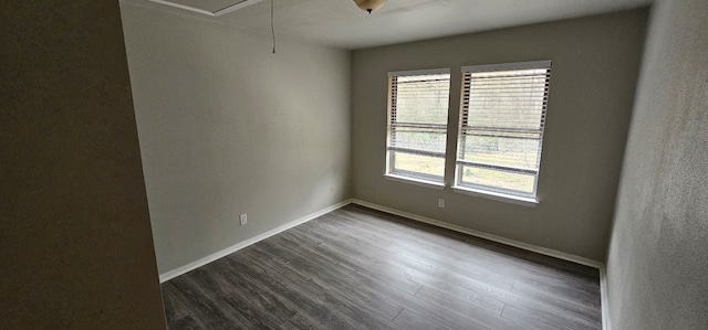 unfurnished room featuring baseboards, attic access, and dark wood-style floors