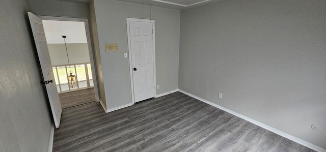 unfurnished bedroom featuring dark wood finished floors, attic access, and baseboards