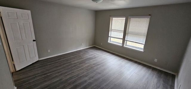 spare room featuring dark wood-type flooring and baseboards