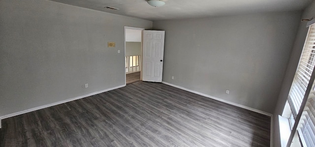 empty room with visible vents, baseboards, and dark wood finished floors