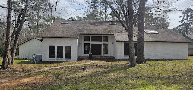 back of property with brick siding and a lawn