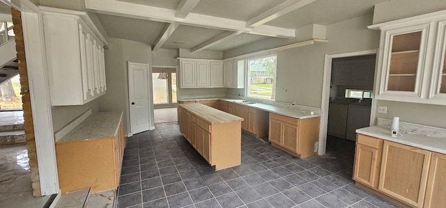 kitchen featuring washer and clothes dryer, a sink, glass insert cabinets, beamed ceiling, and a center island