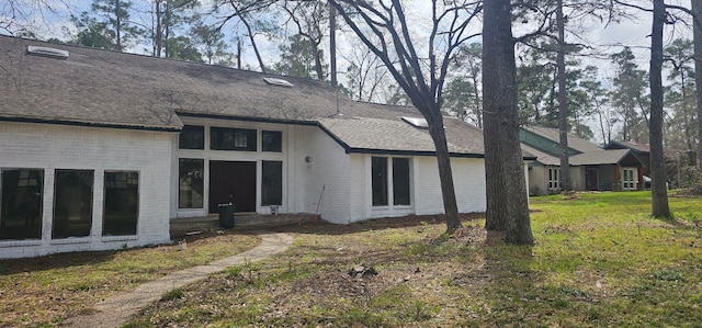 back of property with brick siding, a lawn, and a shingled roof