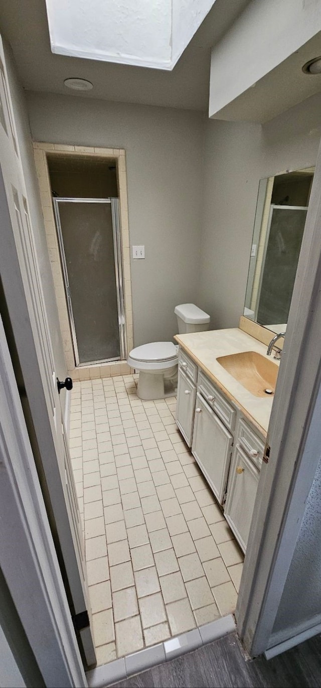 bathroom featuring tile patterned floors, toilet, a stall shower, and vanity