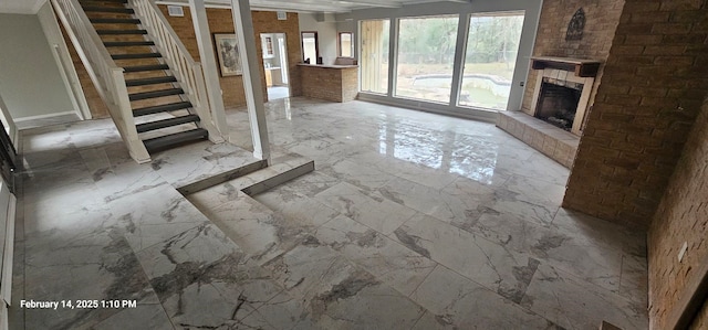 unfurnished living room with stairway, marble finish floor, and a large fireplace