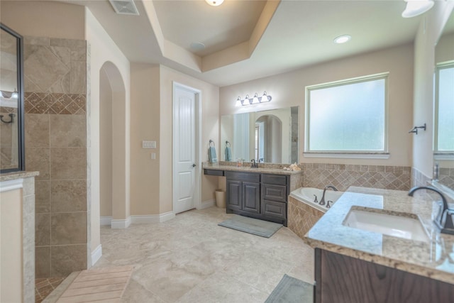 full bath featuring a garden tub, a walk in shower, visible vents, and a sink