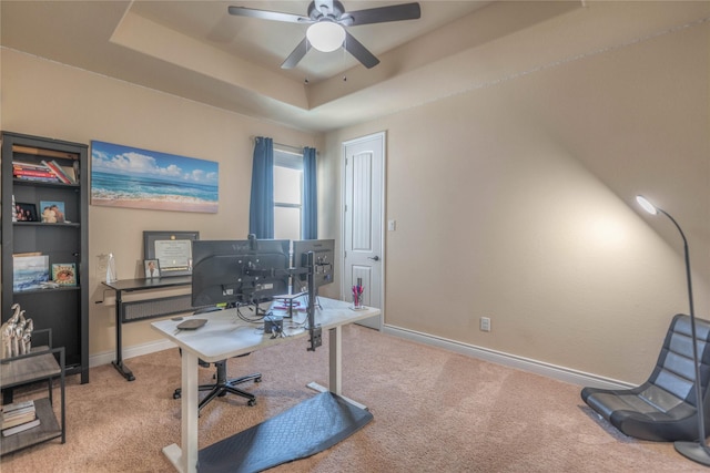 office area with baseboards, a raised ceiling, a ceiling fan, and carpet flooring