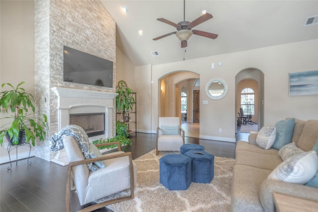 living room featuring a fireplace, wood finished floors, visible vents, and arched walkways