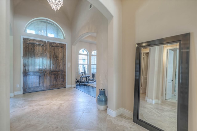 foyer featuring arched walkways, baseboards, and a towering ceiling