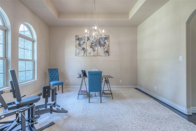 carpeted office space with an inviting chandelier, baseboards, and a tray ceiling