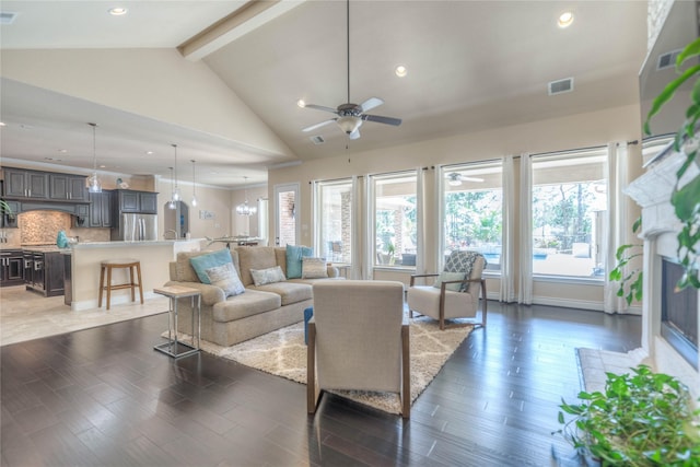 living room featuring visible vents, wood finished floors, a fireplace, ceiling fan, and vaulted ceiling with beams