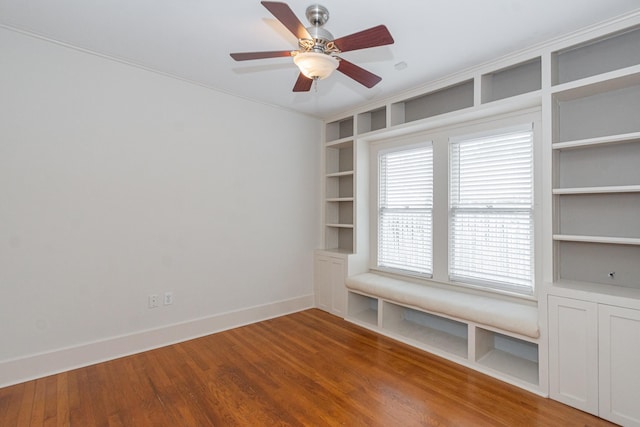 spare room featuring ceiling fan, built in shelves, baseboards, and wood finished floors