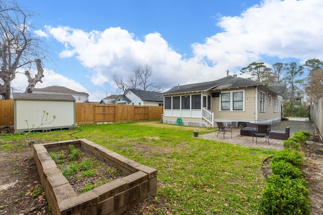 rear view of property with an outbuilding, a fenced backyard, a storage shed, and a sunroom