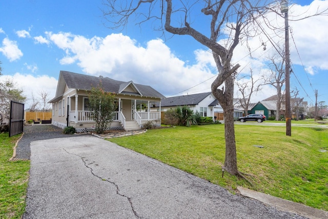 view of front of property featuring driveway, a front lawn, a porch, fence, and roof with shingles