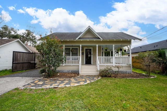 bungalow-style house with a porch, driveway, a front yard, and fence