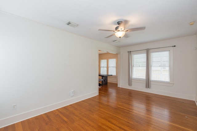 empty room with visible vents, baseboards, wood finished floors, and a ceiling fan