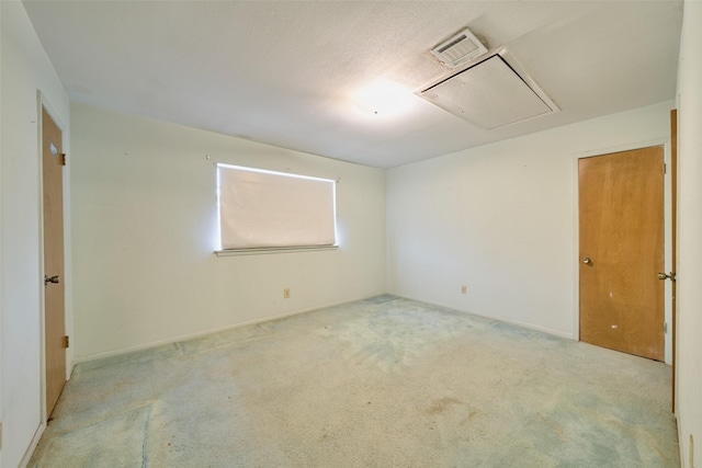 carpeted empty room with visible vents and attic access