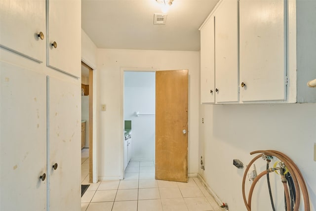 clothes washing area featuring light tile patterned floors, visible vents, cabinet space, and baseboards