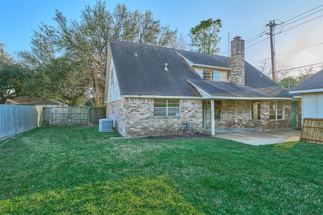 back of property featuring a fenced backyard, a chimney, central air condition unit, a patio area, and a lawn