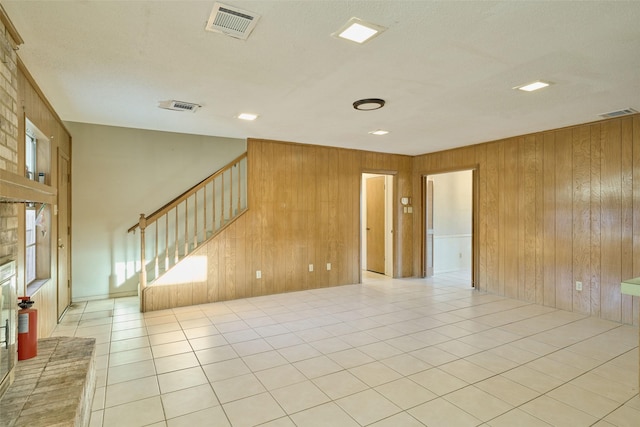 spare room with visible vents, wooden walls, and light tile patterned flooring