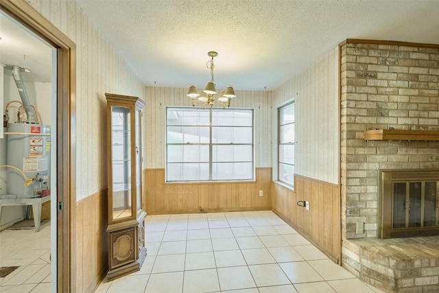 tiled dining room with water heater, a wainscoted wall, a textured ceiling, and wallpapered walls