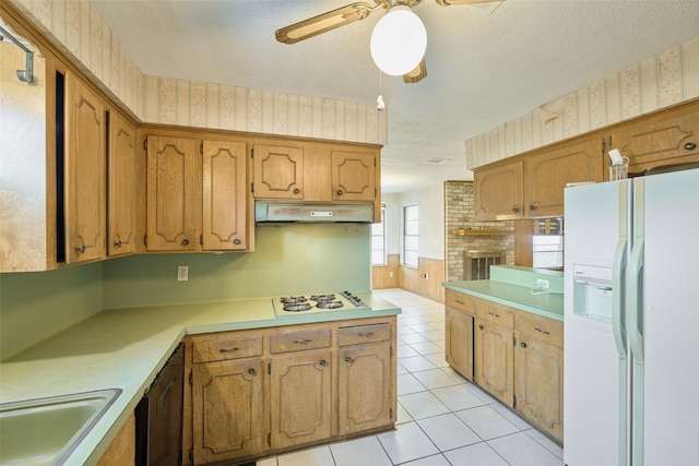 kitchen featuring under cabinet range hood, a textured ceiling, white appliances, light tile patterned flooring, and wallpapered walls