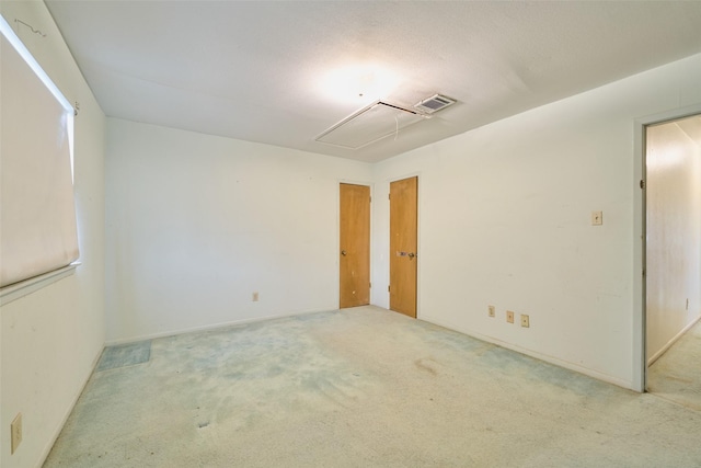 unfurnished room with attic access, visible vents, and carpet floors