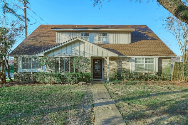 view of front facade with roof with shingles and a front lawn