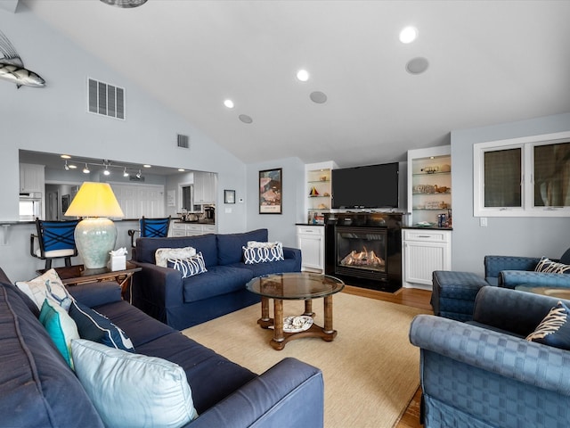 living area featuring light wood finished floors, visible vents, recessed lighting, and a glass covered fireplace