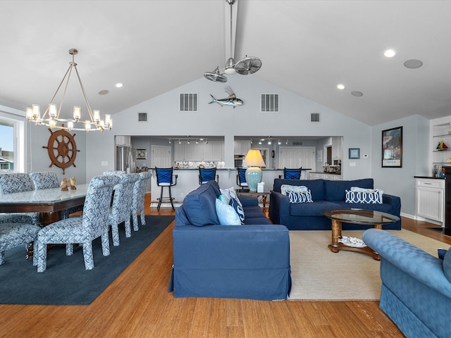 living area featuring visible vents, high vaulted ceiling, and wood finished floors